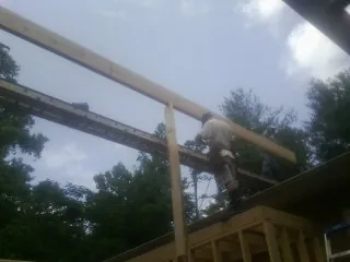 Carpenter setting a ridge beam over a new addition frame — Ice Dam Removal by Roofing Brothers in Horace