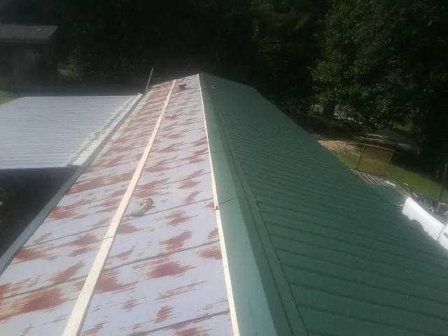 Old rusted panels beside newly installed green metal roofing — Wind Damage Roof Repair by Roofing Brothers in Horace