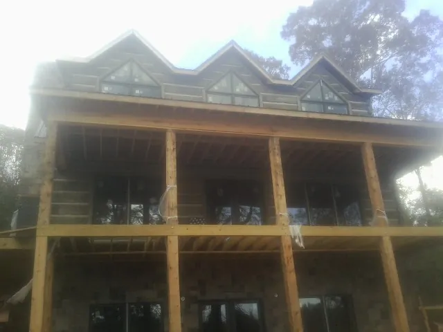 Dormers and porch framing on a large log home under construction — Roof Coating work by our crew in Horace