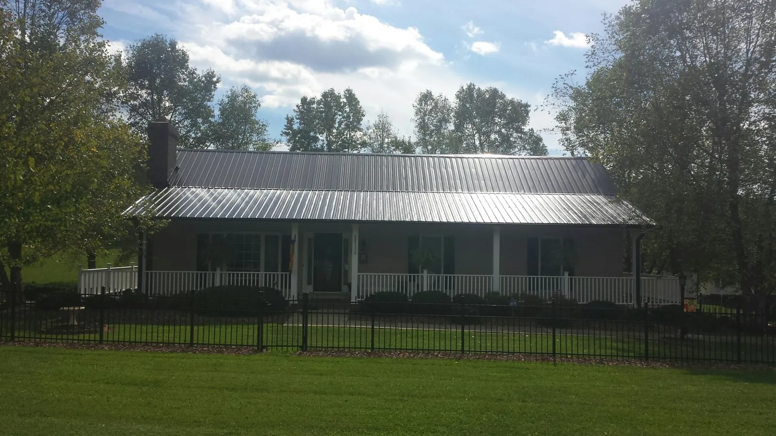 Gray metal roof on a brick ranch with a full width front porch — Gutter Guard Installation work by our crew in Horace